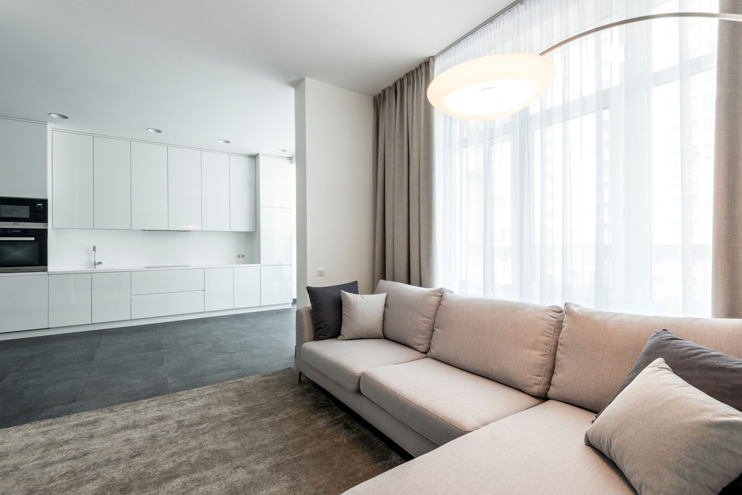 Bright minimalist living room with open kitchen, neutral decor, and cozy atmosphere.